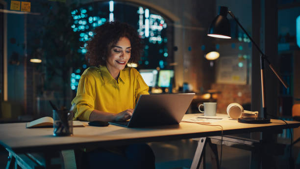 istock Beautiful Middle Eastern Manager Sitting at a Desk in Creative Office in the Evening. Young Stylish Female Using Laptop Computer in Marketing Agency, Developing Projects and Schedules 1481144727