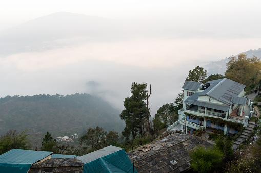 Almora, Uttarakhand, India - April 2019: A vintage bungalow on the edge of a hill with a view of the misty mountains beyond in the Himalayan town of Almora.