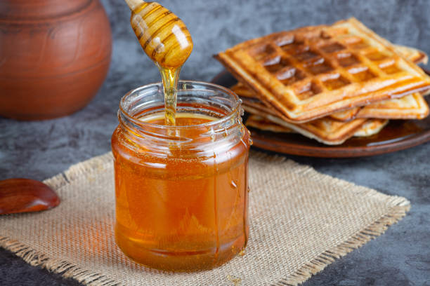 istock Honey in jar with honey dipper and belgian waffles 1481148891