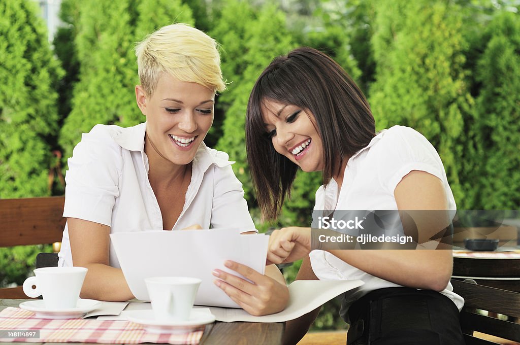 Two businesswoman reading documents Two businesswoman reading documents at coffee break 20-24 Years Stock Photo