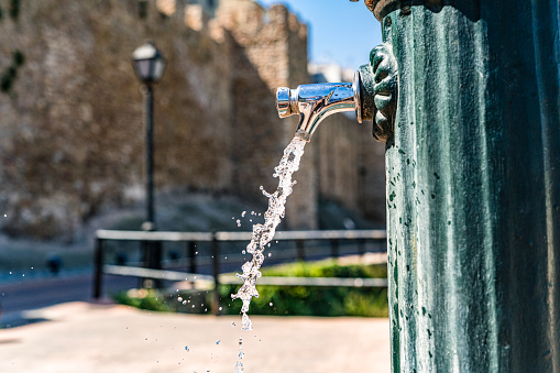 Close up of water flowing from fountain faucet in an old town of Spain. High resolution 42Mp outdoors digital capture taken with SONY A7rII and Zeiss Batis 40mm F2.0 CF lens