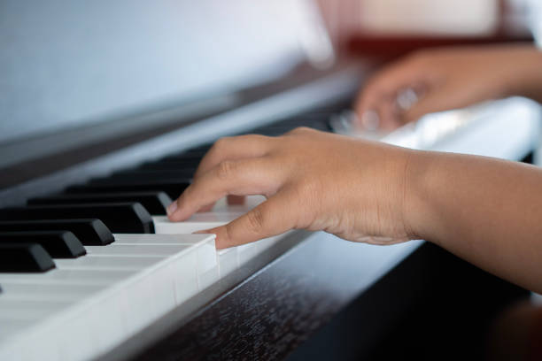 selective focus to kid fingers and piano key to play the piano. there are musical instrument for concert or learning music. - child prodigy imagens e fotografias de stock
