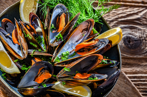 Composition with a plate of steamed mussels served with parsley and lemon