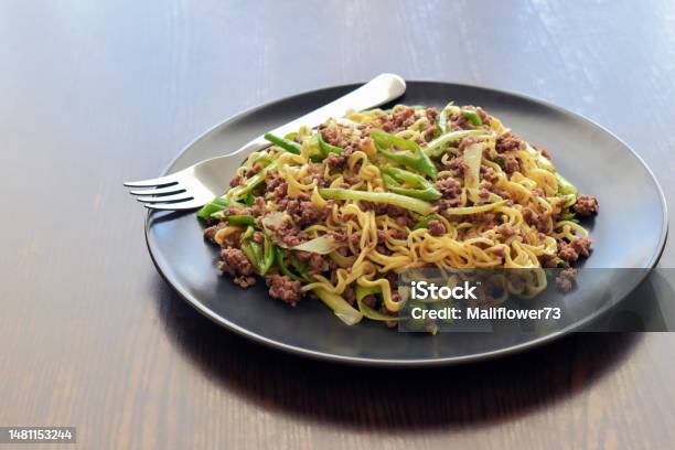 Stir Fry Noodles With Minced Beef Spring Onion And Chillies On A Black Plate Stock Photo - Download Image Now