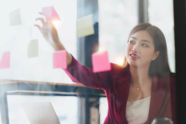 istock Smiling Asian Banker makes financial report and studies annual figures, analyzes profits. Accountant checks status of financial 1481156433