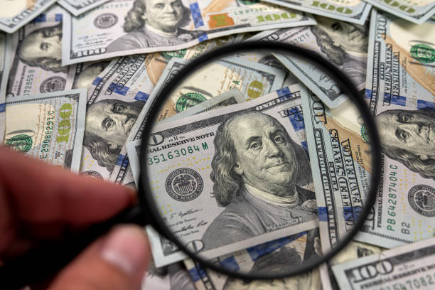 istock magnifying glass magnifier rests on american dollars and magnifies on a white background. 1481158290
