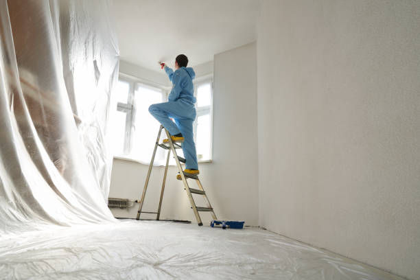 istock Man stands on the stairs and paints the wall with a roller 1481158300