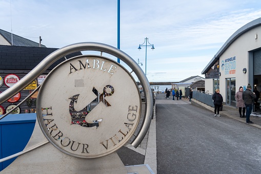 Amble, United Kingdom – March 11, 2023: The entrance sign to the Amble Harbour Village market in the town of Amble, Northumberland, UK.