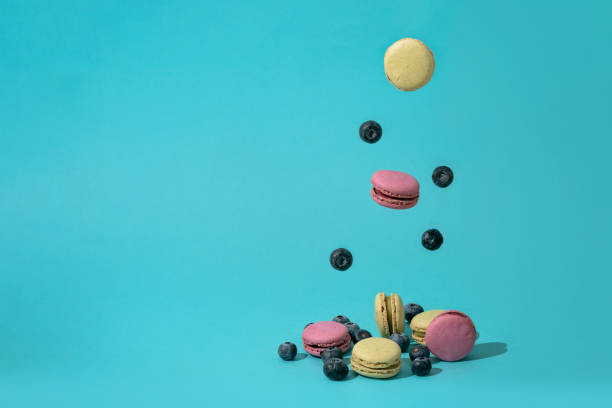 istock Colorful french macaroons and blueberries falling or flying in motion. 1481160822