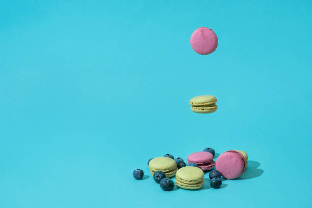istock Colorful french macaroons and blueberries falling or flying in motion. 1481160832
