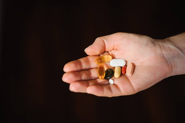 Woman hand with omega 3, multivitamins, vitamins B, C, D, collagen tablets, probiotics, iron capsule. Hand hold supplements on blurred background. Unrecognizable woman takes vitamins daily. Top view. Woman hand with omega 3, multivitamins, vitamins B, C, D, collagen tablets, probiotics, iron capsule. Hand hold supplements on blurred background. Unrecognizable woman takes vitamins daily. Top view. vitamin b 3 stock pictures, royalty-free photos & images