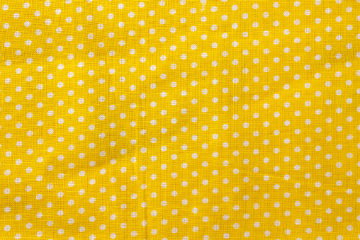 Yellow and white polka dot cotton texture. Fabric textile background