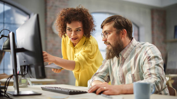 istock Portrait of Two Creative Colleagues Collaborating and Pointing at the Computer in Modern Office. Biracial Female Manager Consults Male Projects Manager, They Brainstorm on the Project. 1481165405