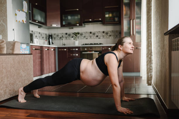 Pregnant woman practice yoga Plank or Phalakasana pose to meditation smile with big belly. Plank exercise. Pregnancy yoga and fitness. Calm female deep breath with fresh air pose comfortably at home. la mujer embarazada practica yoga plank o phalakasana posan para la meditación sonríe con gran barriga. ejercicio de plancha. yoga y fitness durante el embarazo. calma la respiración profunda femenina con aire fresco posa cómodamente en casa.