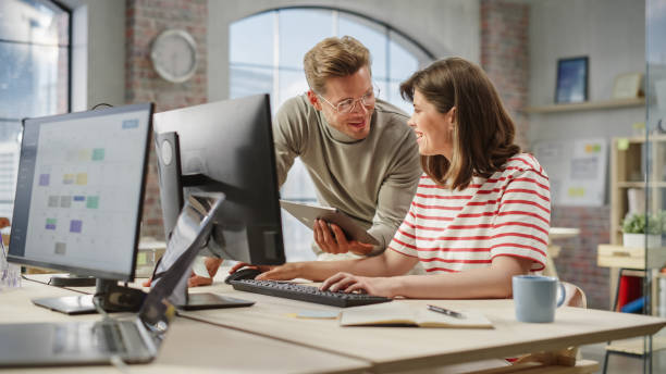 istock Portrait of Two Creative Colleagues Using Computer and Tablet to Discuss Work Project. Young Caucasian Technical Support Specialist Helping Female Customer Relationship Coordinator. Teamwork Concept 1481165454