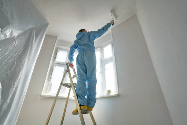 istock Man stands on the stairs and paints the wall with a roller 1481166412