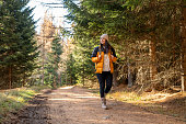 Woman with backpack hiking on footpath in forest at spring