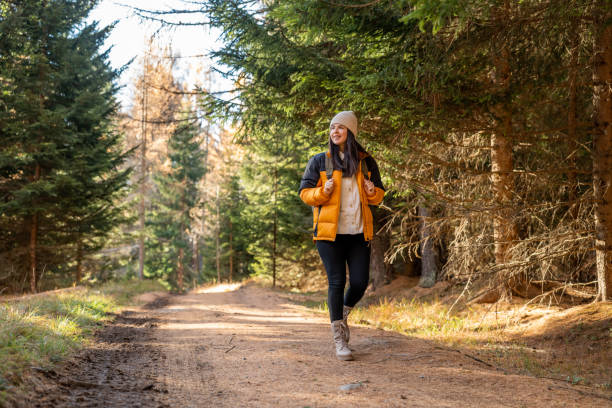 Woman with backpack hiking on footpath in forest at spring stock photo