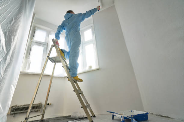 istock Man stands on the stairs and paints the wall with a roller 1481167016