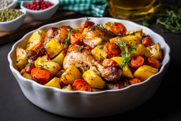 A close-up shot of roasted potatoes and tomatoes with garlic, freshly baked in the oven on a tray. The golden, seasoned potato wedges are paired with sweet, roasted cherry tomatoes, garnished with black pepper, and the garlic cloves, giving off a warm, savory aroma. Perfect for a healthy, easy-to-make side dish.