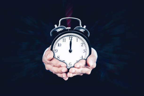istock Man holding wall clock showing twelve o'clock 1481179311