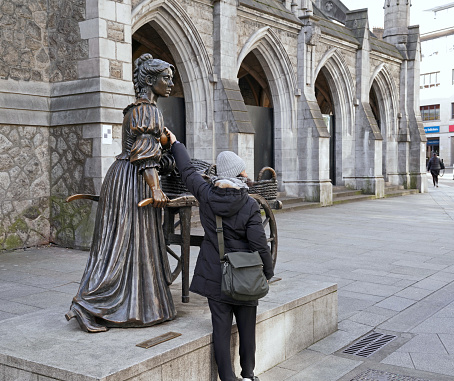 Dublin, Ireland - March 2023:  Molly Malone statue is a popular tourist attraction, people having their pictures taken while touching her breasts in a low cut dress