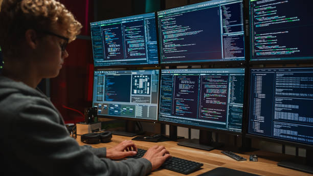 istock Young Caucasian Man Writing Code on Professional Six Monitors Setup in Dark Office. Male Cyber Security Expert Controlling Digital Data Protection System in International Intelligence Agency. 1481183740
