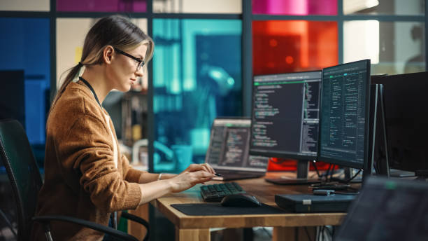 istock Young Caucasian Woman Programming On Desktop Computer With Two Monitors Setup in Spacious Office. Female Software Developer Creating SaaS Platform For Businesses in Innovative Start-up Company. 1481183810