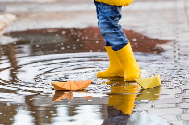 istock It's springtime. A small child in yellow rubber boots jumps through puddles, plays and launches paper boats on the water.. Photo of spring and autumn holidays. The concept of spring. 1481186611