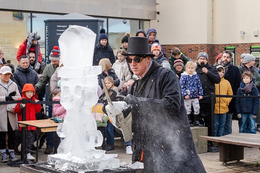 Durham, United Kingdom – February 25, 2023: An artist carves ice with a chainsaw in a demonstration at the Fire and Ice Festival in the city of Durham, UK