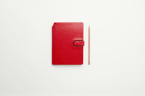 Red personal organiser and a pencil background for design use