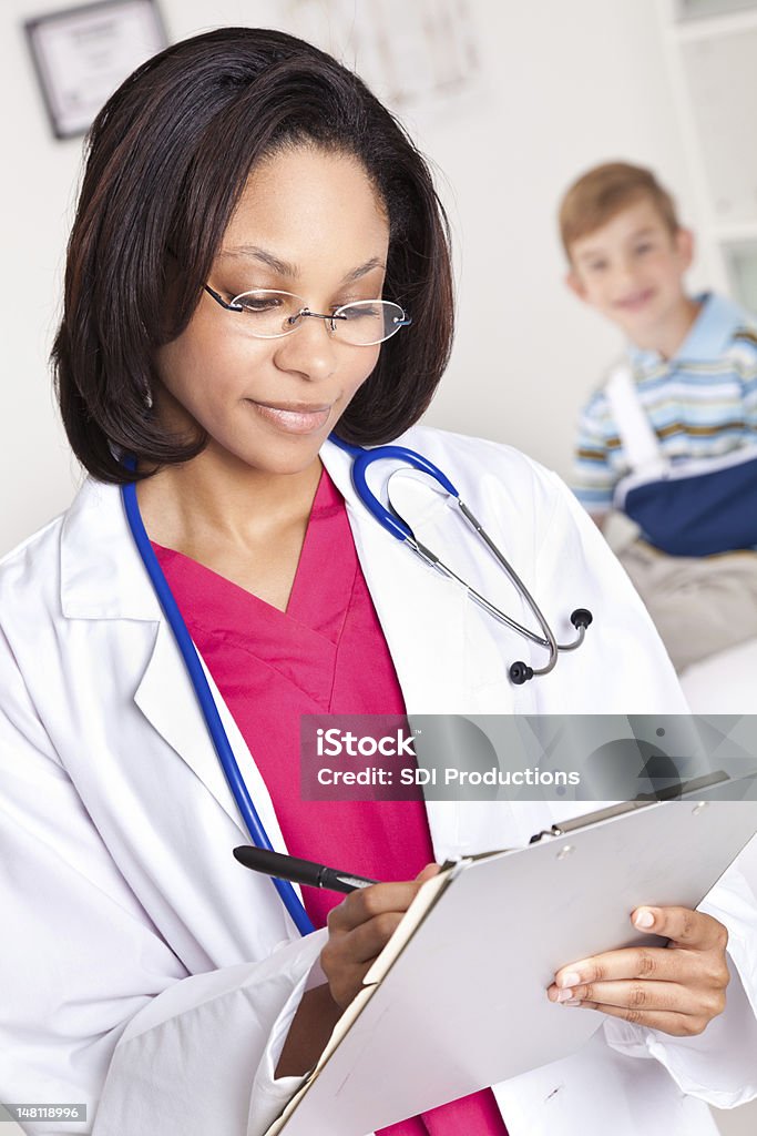 Doctor tomando notas en oficina con paciente detrás de su - Foto de stock de Accidentes y desastres libre de derechos