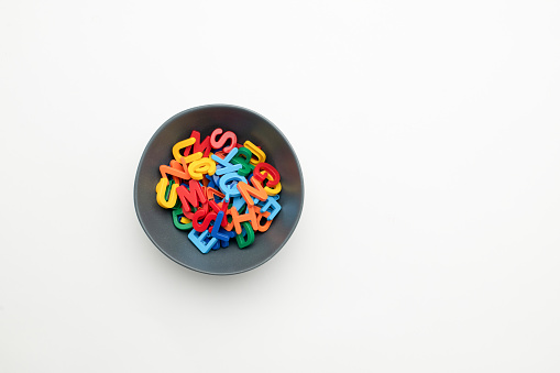 Concept - A bowl containing a random mix of colourful letter magnets
