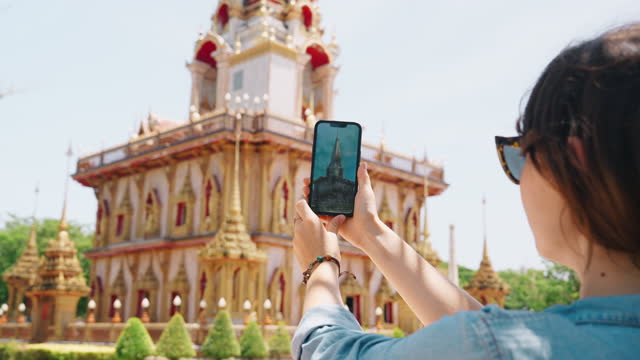 Woman photographing  Wat Chalong with smartphone