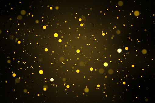 Abstract defocused lights and bokeh on dark background. Gold sparkles and glitter on black background.
