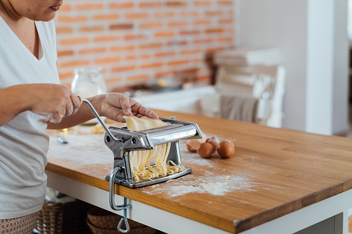 Woman making home made pasta on a counter top in the kitchen