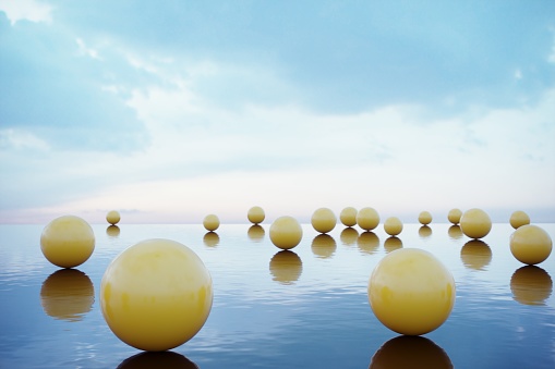 Yellowish colored balls standing on the reflective water . (3d render)