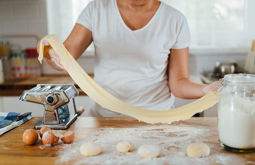 Woman making home made pasta on a counter top in the kitchen