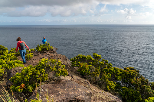 Two woman looking at the view of the volcano's basalt cliff in Terceira, Azores,