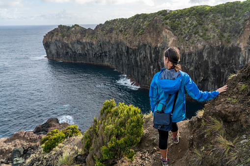 Woman looking at the view of the volcano's basalt cliff in terceira. Azores,