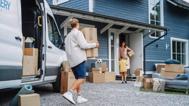 istock Handsome Man Unloading a Cargo Van Full of Cardboard Moving Boxes. Young Happy Family with a Son Moving to Their Dream Home in the Suburbs. Delivery Transportation Car Sharing Service. 1481194502