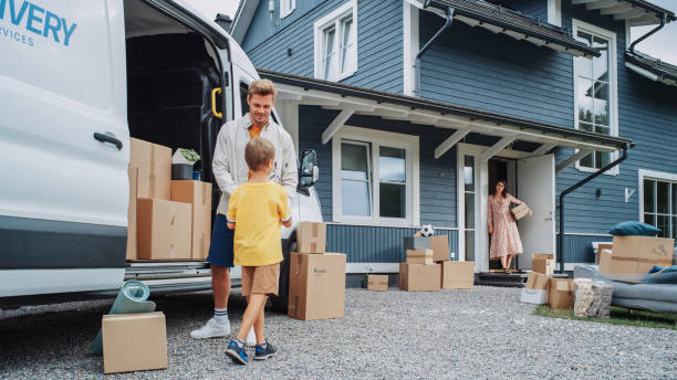 istock Handsome Man Unloading a Cargo Van Full of Cardboard Moving Boxes. Young Happy Family with a Son Moving to Their Dream Home in the Suburbs. Delivery Transportation Car Sharing Service. 1481194526