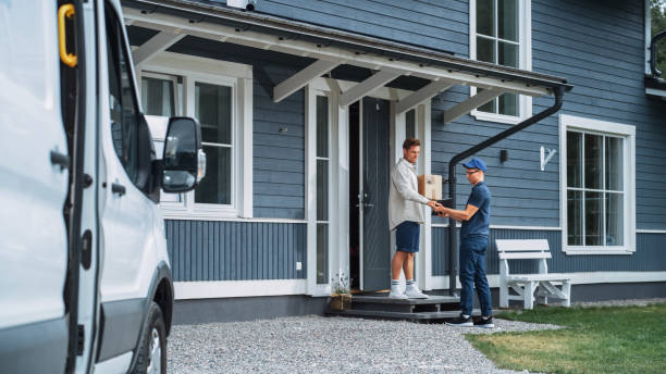 istock Handsome Young Homeowner Receiving an Awaited Parcel from a Cheerful Courier. Postal Service Worker Comes to the House to Make a Door to Door Delivery and Get a POD Signature on Tablet. 1481194851