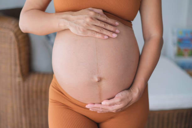 mujer indonesia embarazada irreconocible tocando su gran vientre - holding belly fotografías e imágenes de stock