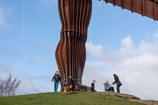 Gateshead, United Kingdom – February 25, 2023: Visitors around the feet of Antony Gormley's landmark sculpture The Angel of the North in Gateshead, UK.