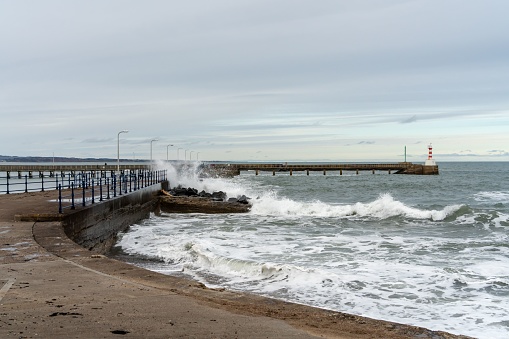 View of waves crashing at the harbour wall in Amble, Northumberland, UK