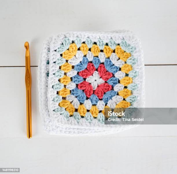 Multicolored Granny Squares With Crochet Hook And White Wooden Ground Stock Photo - Download Image Now