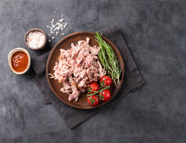 istock Traditional barbecue torn pork meat with bbq sauce, fresh tomatoes and herbs on a dark background. 1481199521