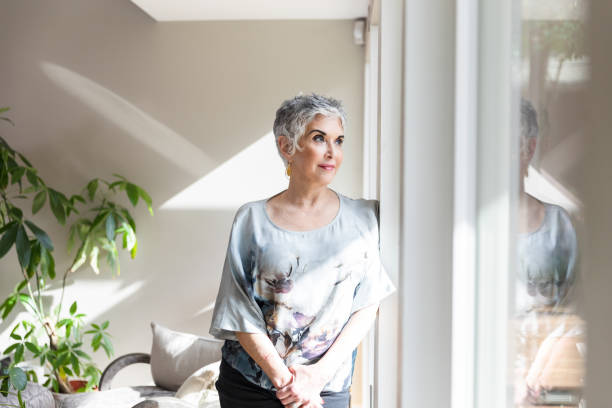 istock Mature woman gazes outside while standing in her dining room 1481199882