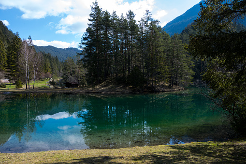 idyllic mountain lake with reflecting surface and crystal clear water surrounded by forest meadows and high mountains and a wooden hut on the lake in Tyrol